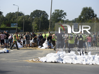 People and members of the territorial defense army fill bags with sand as they prepare for the flood wave to reach the southwestern city of...