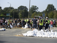 People and members of the territorial defense army fill bags with sand as they prepare for the flood wave to reach the southwestern city of...