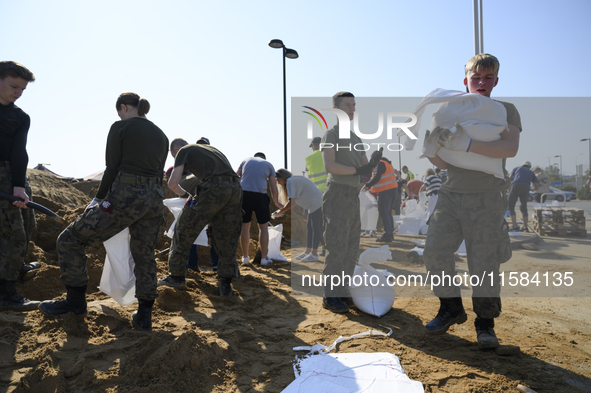 People and members of the territorial defense army fill bags with sand as they prepare for the flood wave to reach the southwestern city of...