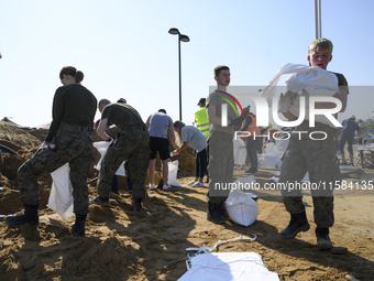 People and members of the territorial defense army fill bags with sand as they prepare for the flood wave to reach the southwestern city of...