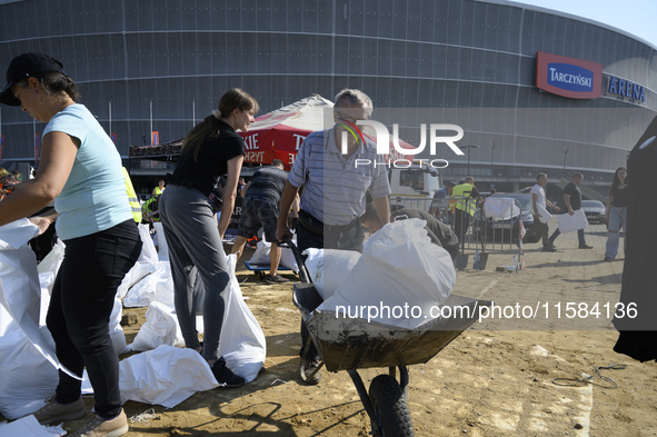 People and members of the territorial defense army fill bags with sand as they prepare for the flood wave to reach the southwestern city of...