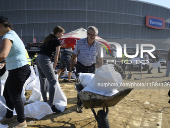 People and members of the territorial defense army fill bags with sand as they prepare for the flood wave to reach the southwestern city of...