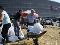 People and members of the territorial defense army fill bags with sand as they prepare for the flood wave to reach the southwestern city of...