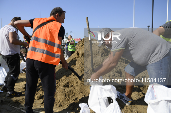 People and members of the territorial defense army fill bags with sand as they prepare for the flood wave to reach the southwestern city of...