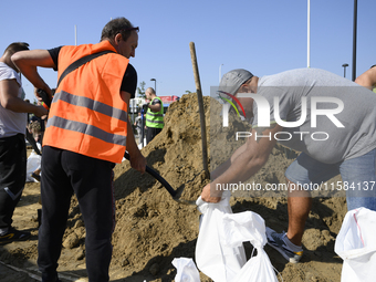 People and members of the territorial defense army fill bags with sand as they prepare for the flood wave to reach the southwestern city of...