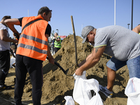 People and members of the territorial defense army fill bags with sand as they prepare for the flood wave to reach the southwestern city of...