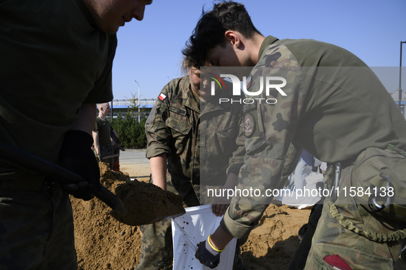 People and members of the territorial defense army fill bags with sand as they prepare for the flood wave to reach the southwestern city of...