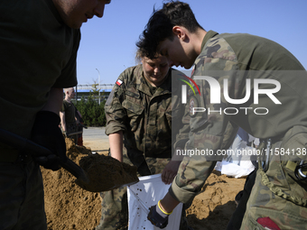 People and members of the territorial defense army fill bags with sand as they prepare for the flood wave to reach the southwestern city of...