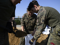 People and members of the territorial defense army fill bags with sand as they prepare for the flood wave to reach the southwestern city of...