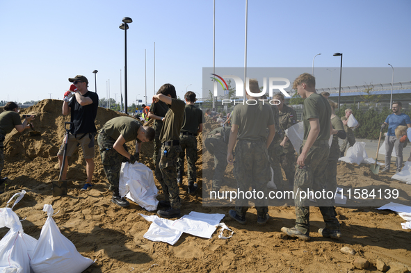 People and members of the territorial defense army fill bags with sand as they prepare for the flood wave to reach the southwestern city of...