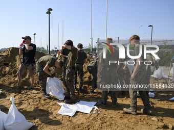 People and members of the territorial defense army fill bags with sand as they prepare for the flood wave to reach the southwestern city of...