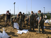 People and members of the territorial defense army fill bags with sand as they prepare for the flood wave to reach the southwestern city of...