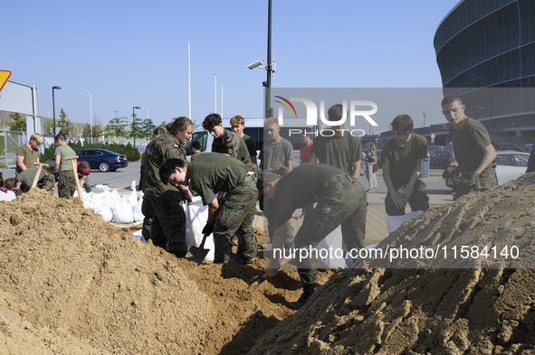 People and members of the territorial defense army fill bags with sand as they prepare for the flood wave to reach the southwestern city of...