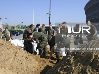 People and members of the territorial defense army fill bags with sand as they prepare for the flood wave to reach the southwestern city of...