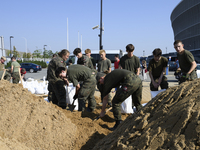 People and members of the territorial defense army fill bags with sand as they prepare for the flood wave to reach the southwestern city of...