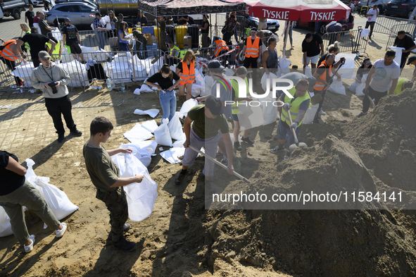 People and members of the territorial defense army fill bags with sand as they prepare for the flood wave to reach the southwestern city of...