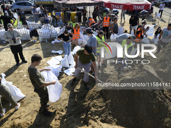 People and members of the territorial defense army fill bags with sand as they prepare for the flood wave to reach the southwestern city of...