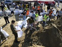 People and members of the territorial defense army fill bags with sand as they prepare for the flood wave to reach the southwestern city of...