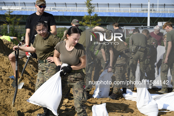 People and members of the territorial defense army fill bags with sand as they prepare for the flood wave to reach the southwestern city of...