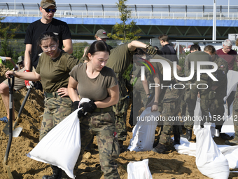 People and members of the territorial defense army fill bags with sand as they prepare for the flood wave to reach the southwestern city of...