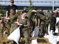 People and members of the territorial defense army fill bags with sand as they prepare for the flood wave to reach the southwestern city of...