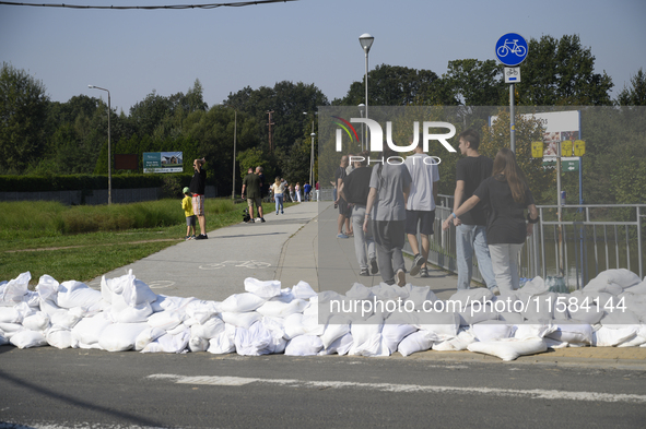 People walk past sandbags as they prepare for the flood wave to reach the southwestern city of Wroclaw, Poland, on September 18, 2024. The g...