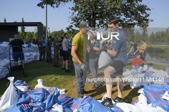 People and members of the territorial defense army fill bags with sand as they prepare for the flood wave to reach the southwestern city of...