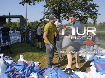 People and members of the territorial defense army fill bags with sand as they prepare for the flood wave to reach the southwestern city of...