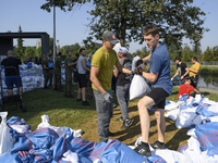 People and members of the territorial defense army fill bags with sand as they prepare for the flood wave to reach the southwestern city of...