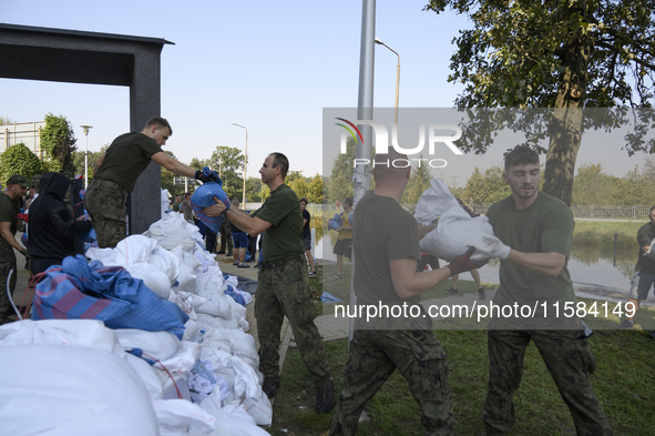 People and members of the territorial defense army fill bags with sand as they prepare for the flood wave to reach the southwestern city of...