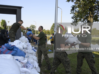 People and members of the territorial defense army fill bags with sand as they prepare for the flood wave to reach the southwestern city of...