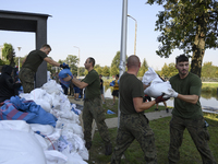 People and members of the territorial defense army fill bags with sand as they prepare for the flood wave to reach the southwestern city of...