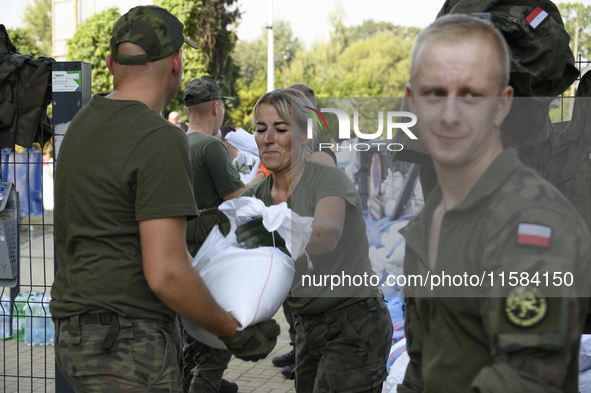 People and members of the territorial defense army fill bags with sand as they prepare for the flood wave to reach the southwestern city of...