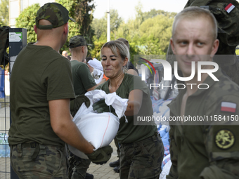 People and members of the territorial defense army fill bags with sand as they prepare for the flood wave to reach the southwestern city of...