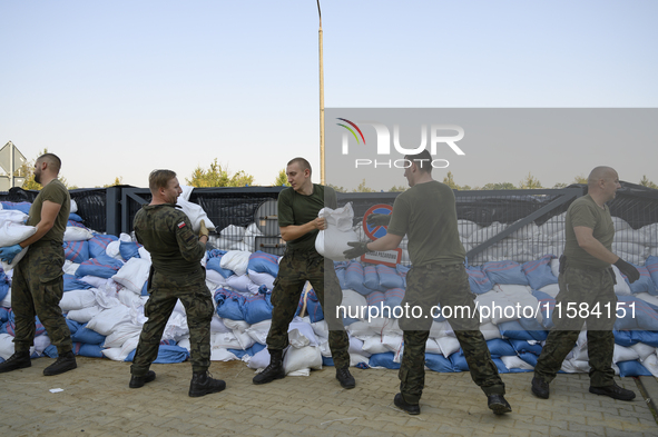 People and members of the territorial defense army fill bags with sand as they prepare for the flood wave to reach the southwestern city of...