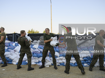 People and members of the territorial defense army fill bags with sand as they prepare for the flood wave to reach the southwestern city of...