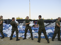 People and members of the territorial defense army fill bags with sand as they prepare for the flood wave to reach the southwestern city of...