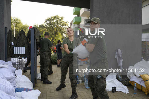 People and members of the territorial defense army fill bags with sand as they prepare for the flood wave to reach the southwestern city of...