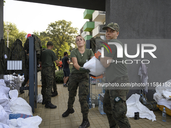 People and members of the territorial defense army fill bags with sand as they prepare for the flood wave to reach the southwestern city of...