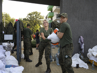 People and members of the territorial defense army fill bags with sand as they prepare for the flood wave to reach the southwestern city of...