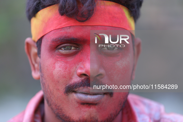 A Nepali Hindu devotee's face is smeared with vermillion powder as he takes part in the immersion ceremony of eco-friendly Lord Bishwokarma...