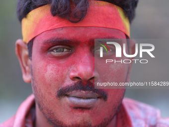 A Nepali Hindu devotee's face is smeared with vermillion powder as he takes part in the immersion ceremony of eco-friendly Lord Bishwokarma...