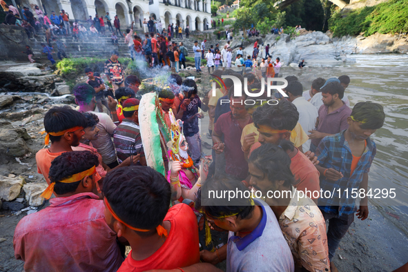 Nepali Hindu devotees perform rituals before they immerse an eco-friendly idol of the Hindu god Bishwokarma in the Bagmati River in Kathmand...