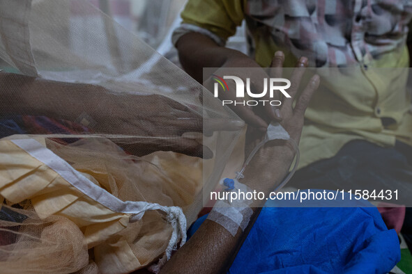 Rina Begum (70) suffers for a week and is admitted last night due to dengue fever. She points to the saline cannula as she feels discomfort...