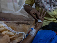 Rina Begum (70) suffers for a week and is admitted last night due to dengue fever. She points to the saline cannula as she feels discomfort...