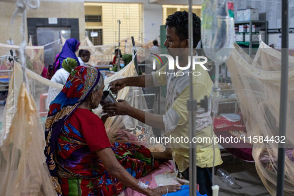 Rina Begum (70) drinks juice from her son's hand as she is admitted to the hospital due to dengue fever in Dhaka, Bangladesh, on September 1...