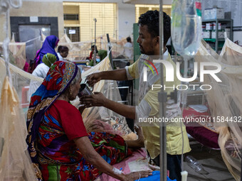 Rina Begum (70) drinks juice from her son's hand as she is admitted to the hospital due to dengue fever in Dhaka, Bangladesh, on September 1...