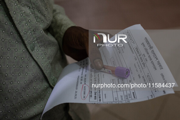 An attendant of a dengue patient submits a blood sample to the lab while Jannatul Fedaus Maya (17), a dengue patient with breathing problems...