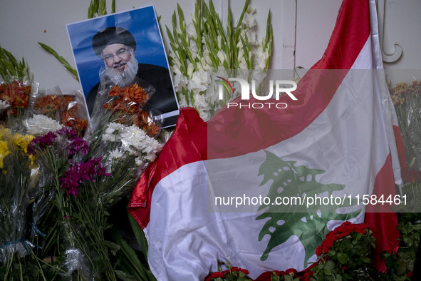 A portrait of Lebanon Hezbollah's Secretary-General Hassan Nasrallah and a Lebanese flag are pictured next to flowers placed in front of the...