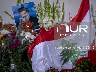 A portrait of Lebanon Hezbollah's Secretary-General Hassan Nasrallah and a Lebanese flag are pictured next to flowers placed in front of the...